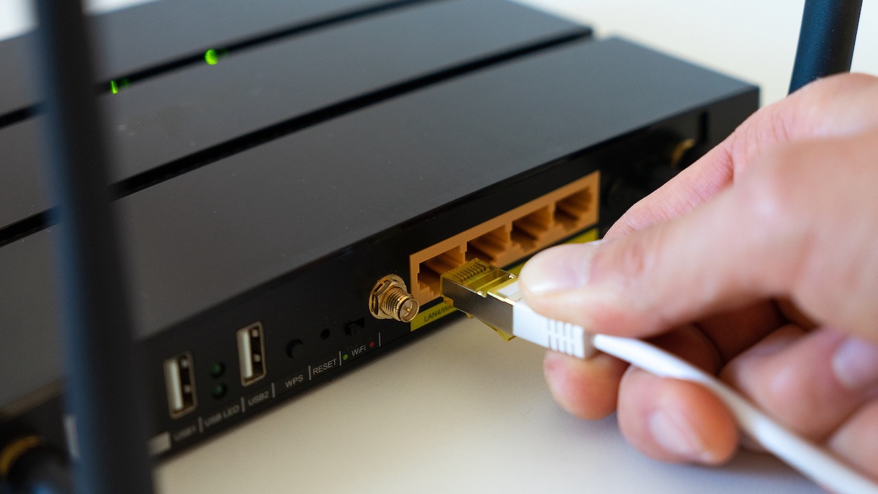 hand plugging in ethernet cable to a wireless router