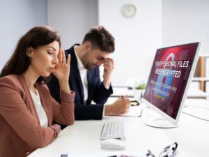 Man and woman concerned looking at hacked computer screen