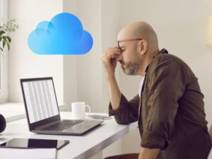 STRESSED MAN ON COMPUTER WITH ICLOUD ICON