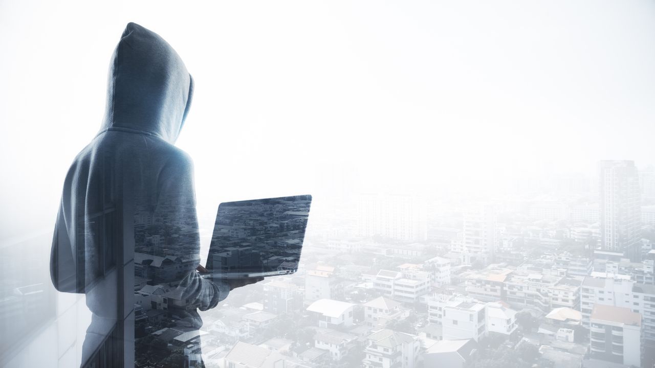person in a hood holding a computer