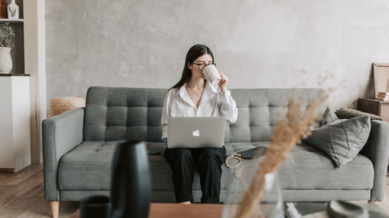 person using computer sitting on sofa