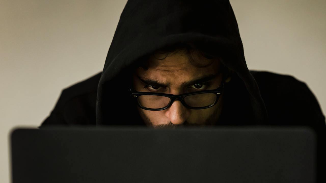 Black hooded hacker with black glasses