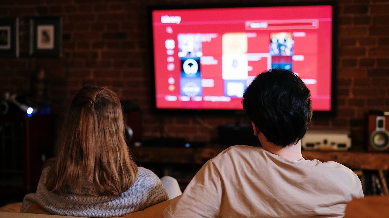 Couple sitting in front of tv choosing streaming service