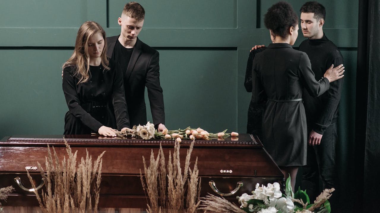 grieving family laying flowers on wooden casket