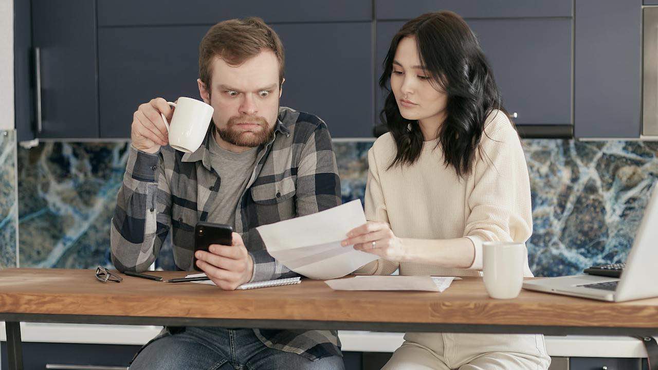 Man sitting with woman looking aghast while holding coffee