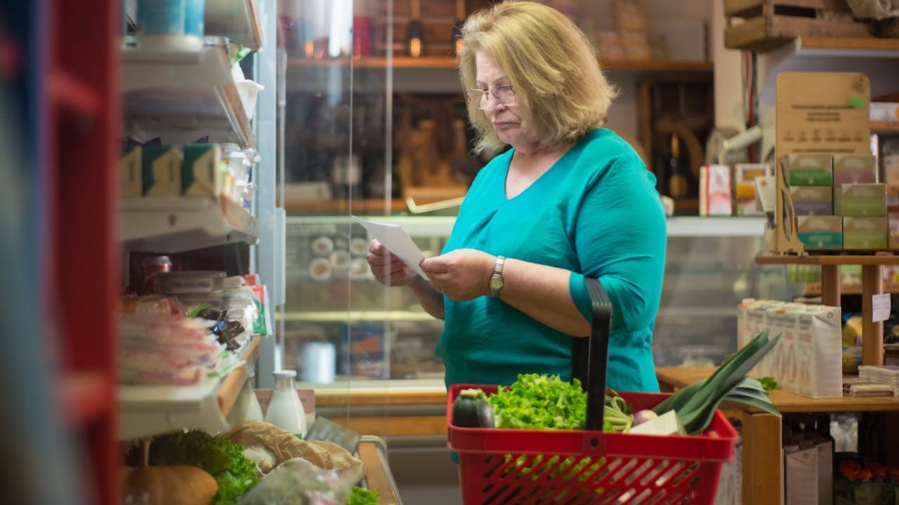 woman in green shirt looking at her grocery list