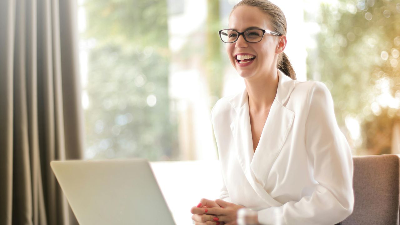 Laughing businesswoman working in office with laptop