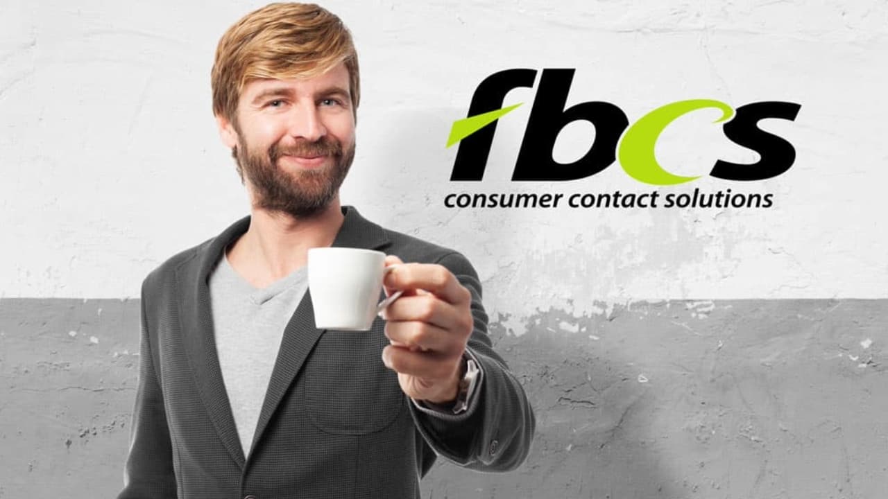 A person holding coffee cup in hand with FBCS logo in the background.