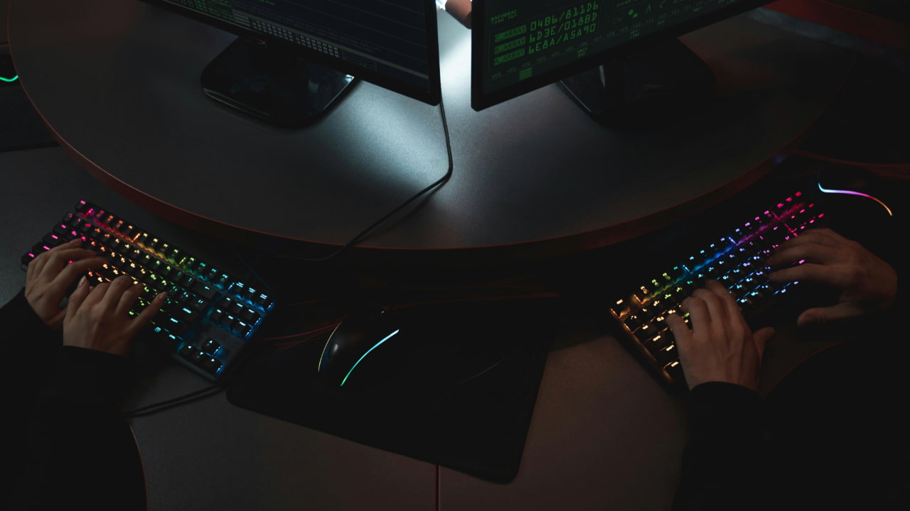 Two people using computers in a dark room.