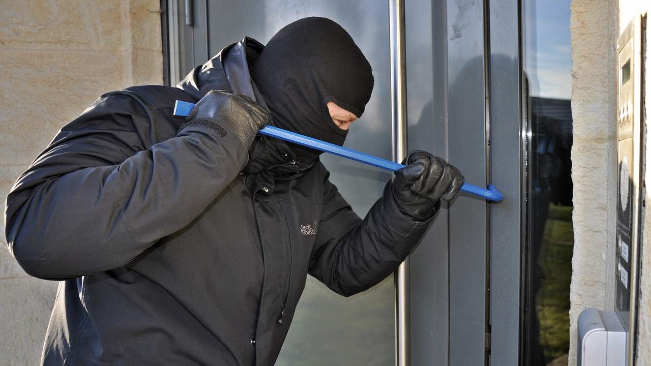 Burglar with mask breaking in with a crowbar