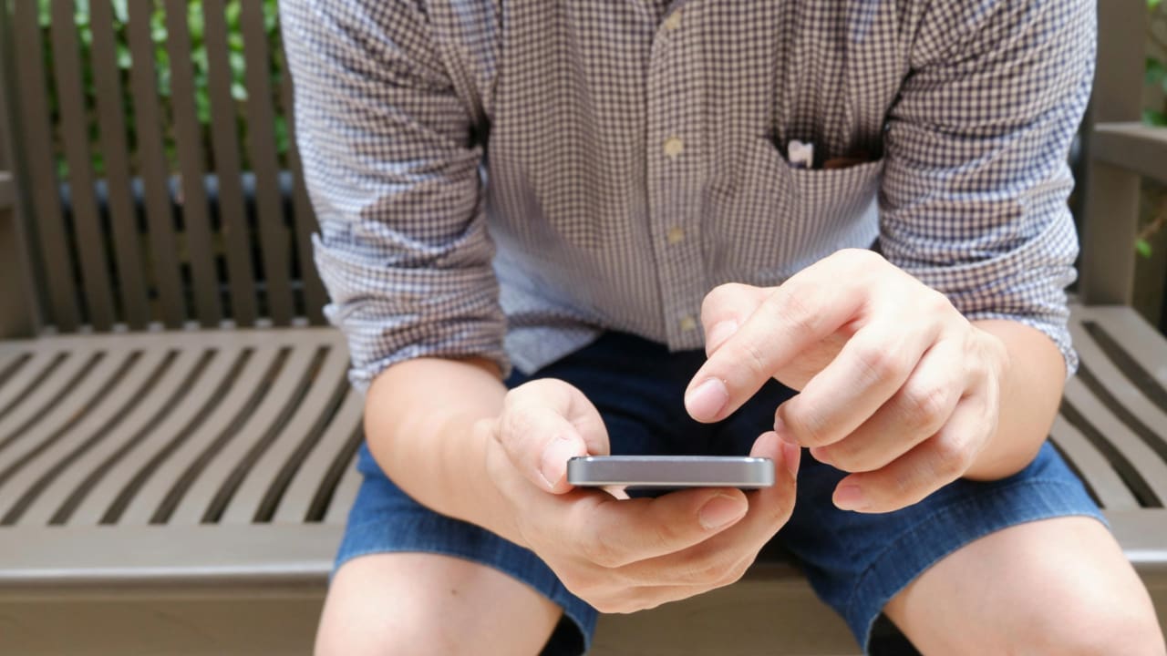 A person sitting on a bench using a phone.