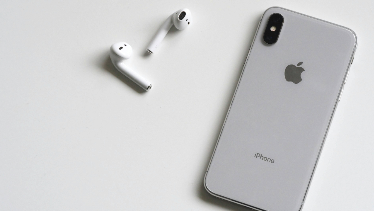 A stock photo of an iPhone SE next to a pair of Apple AirPods. 