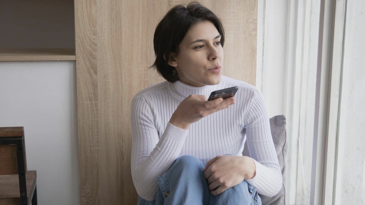 woman in white turtleneck speaking on phone