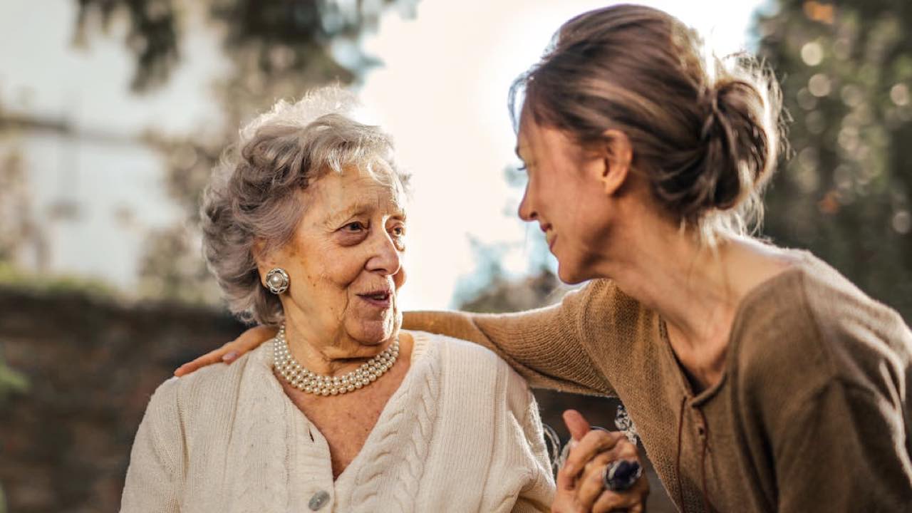 Joyful adult daughter greeting happy surprised senior mother in garden