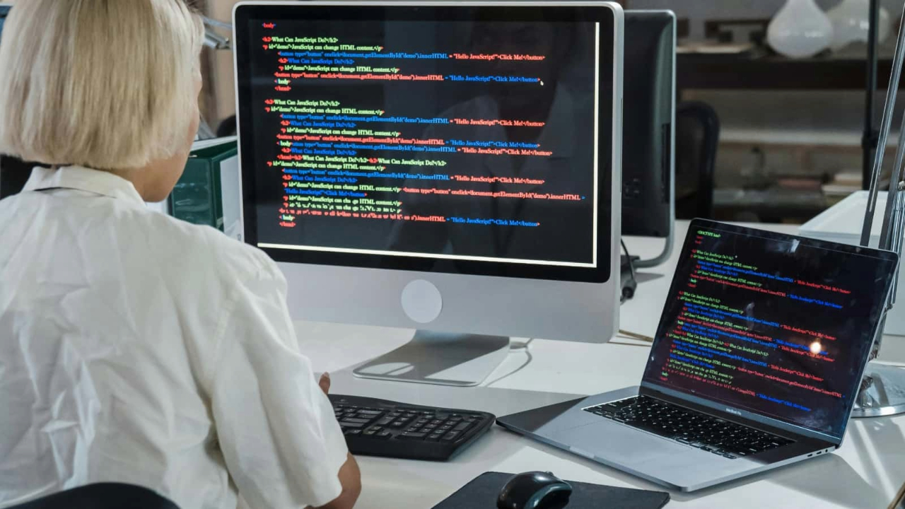 A person using a computer which shows code running.