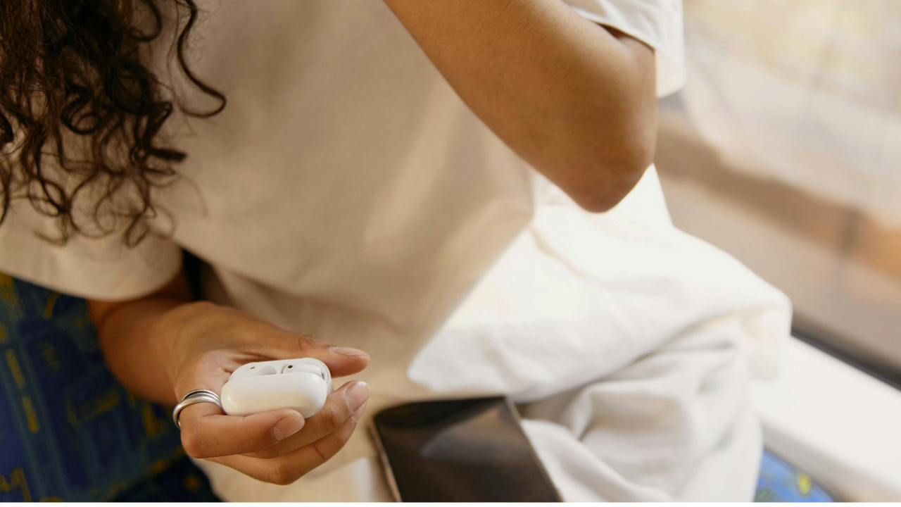 A stock photo showing a hand holding the Apple AirPod Pro 2 earbuds.