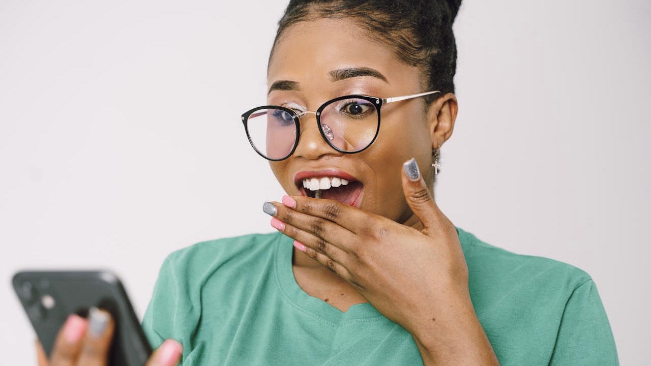 Shocked Woman in Glasses Looking at Cellphone Screen