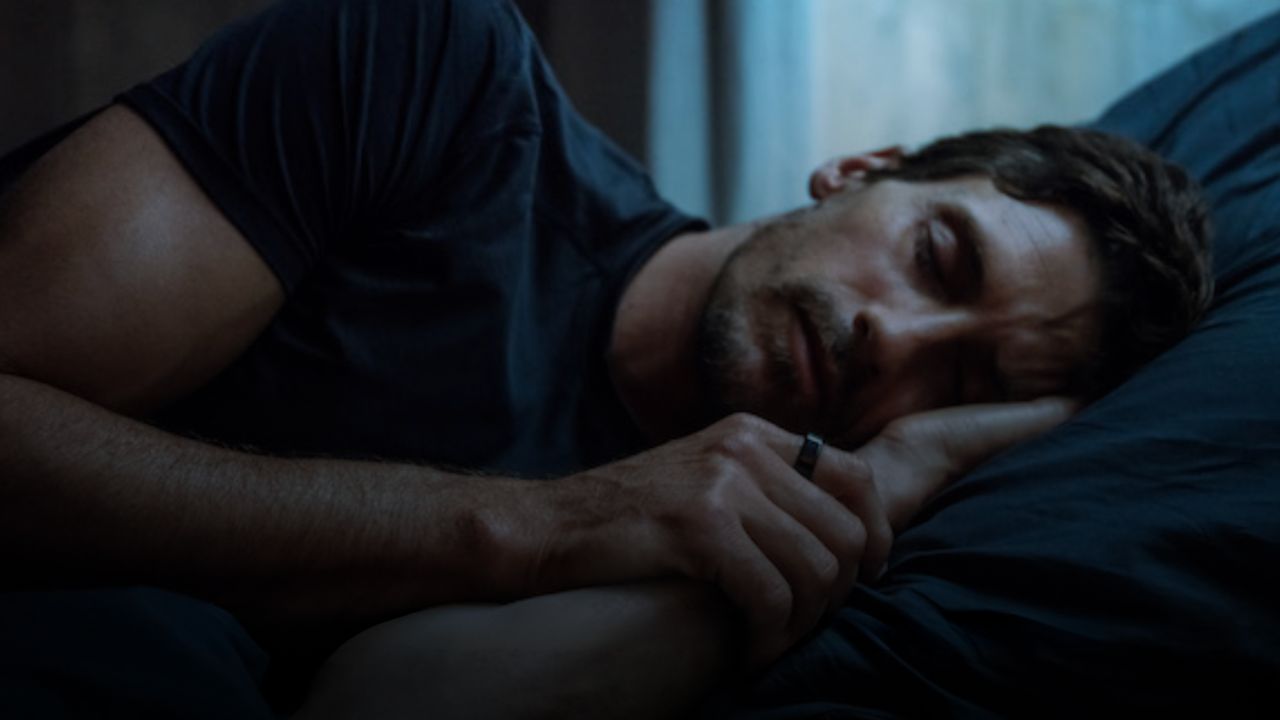 Image of man sleeping with Oura ring on his finger 