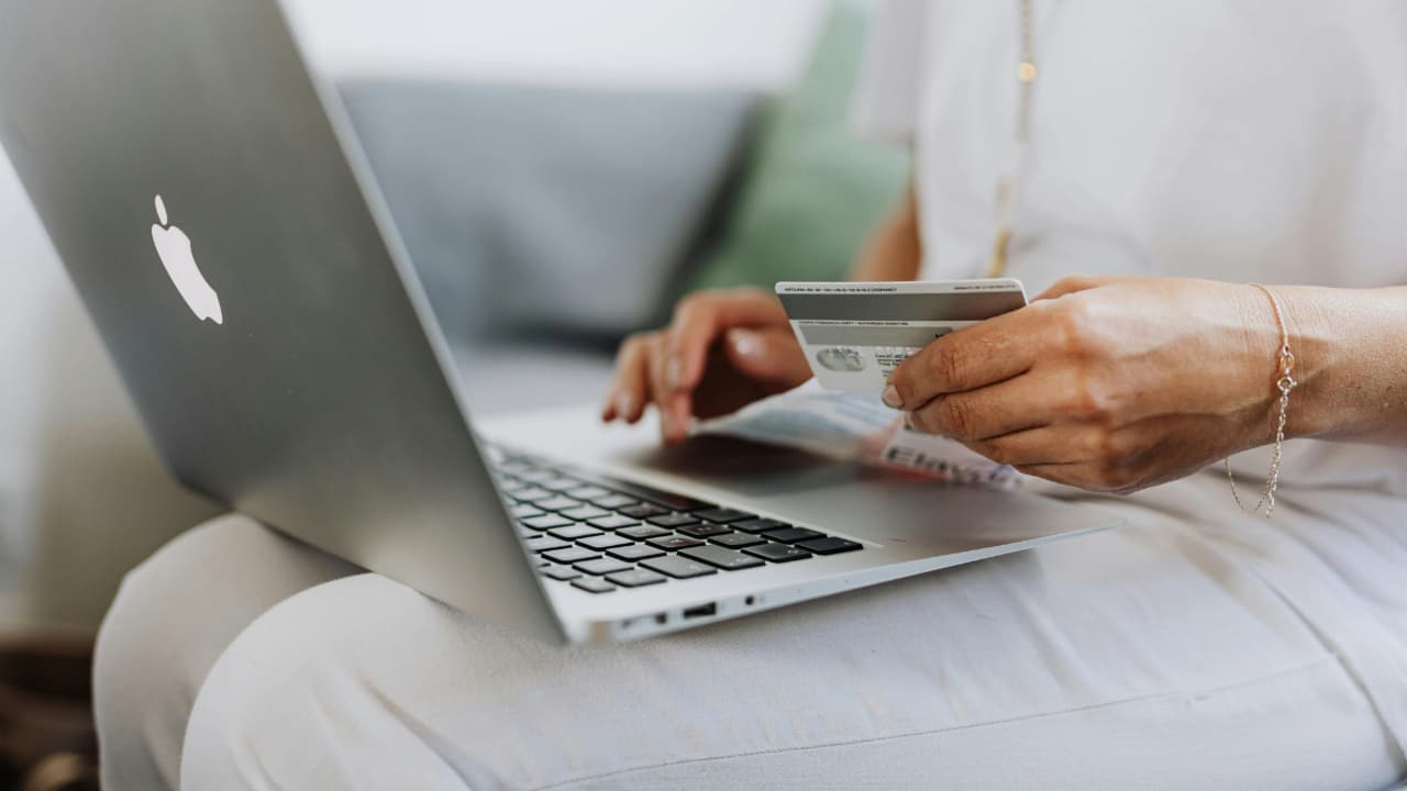 A person using a laptop with card in one hand