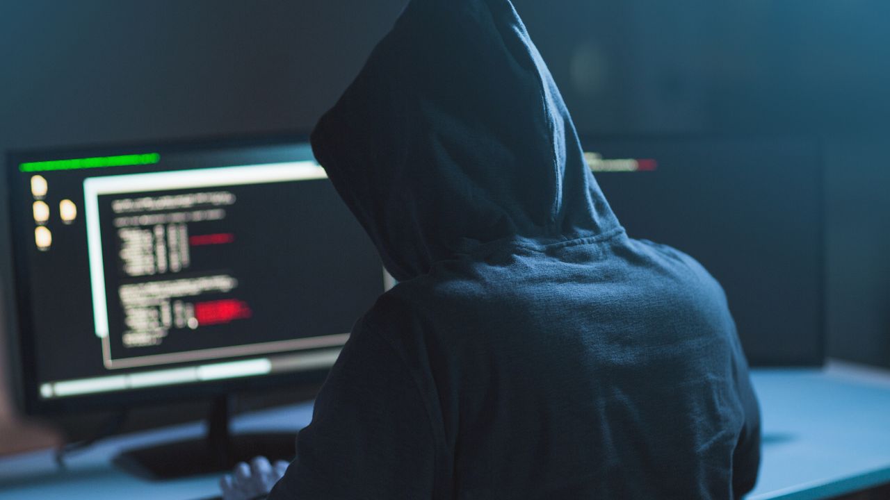 A person wearing a hoodie using a computer