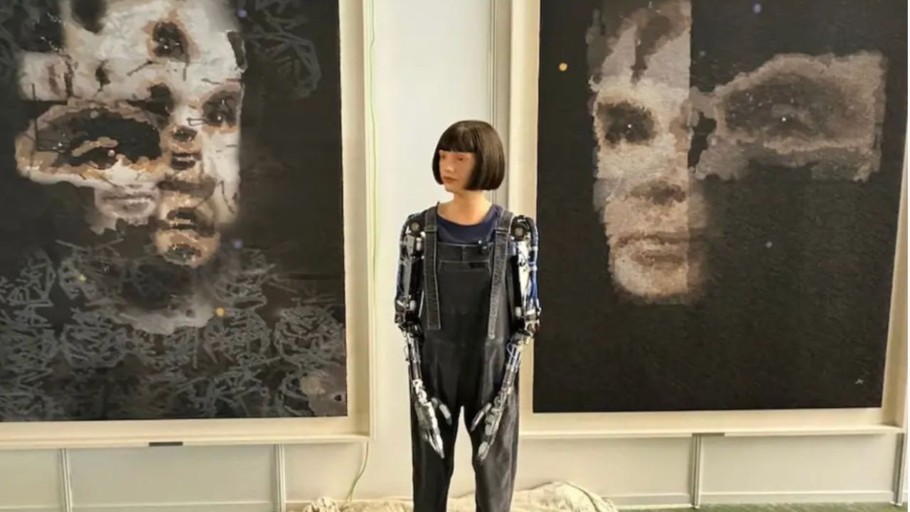 Ai-Da humanoid robot artist in front of her creations 