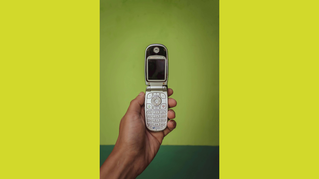 A stock photo of a flip phone with a green background.