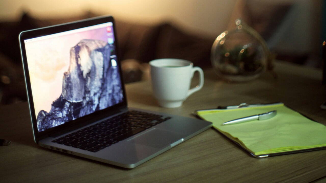 A macbook next to a coffee mug