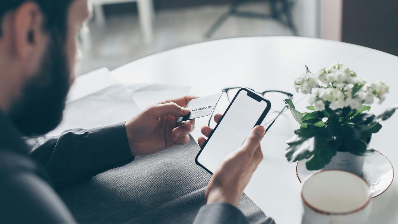 man holding phone and credit card