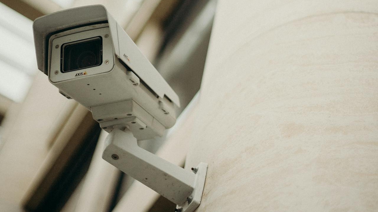 A white surveillance camera mounted on a wall.