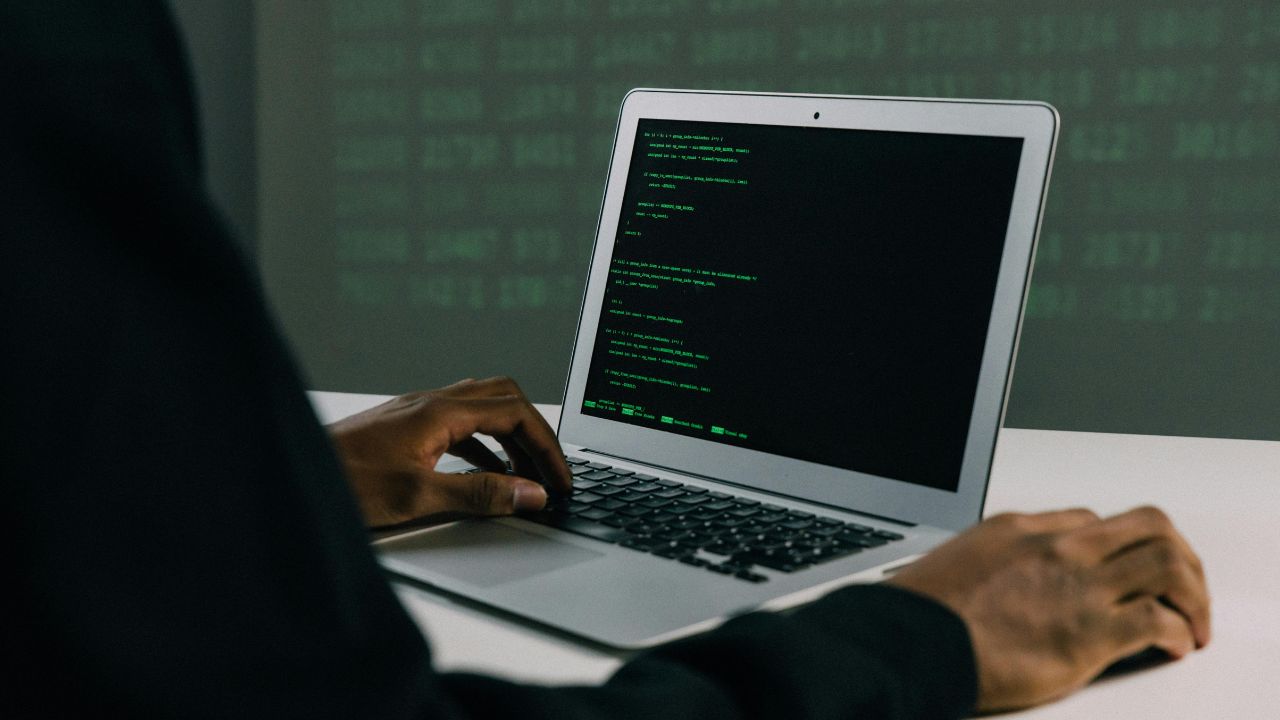 Close-up of hands typing code on laptop screen