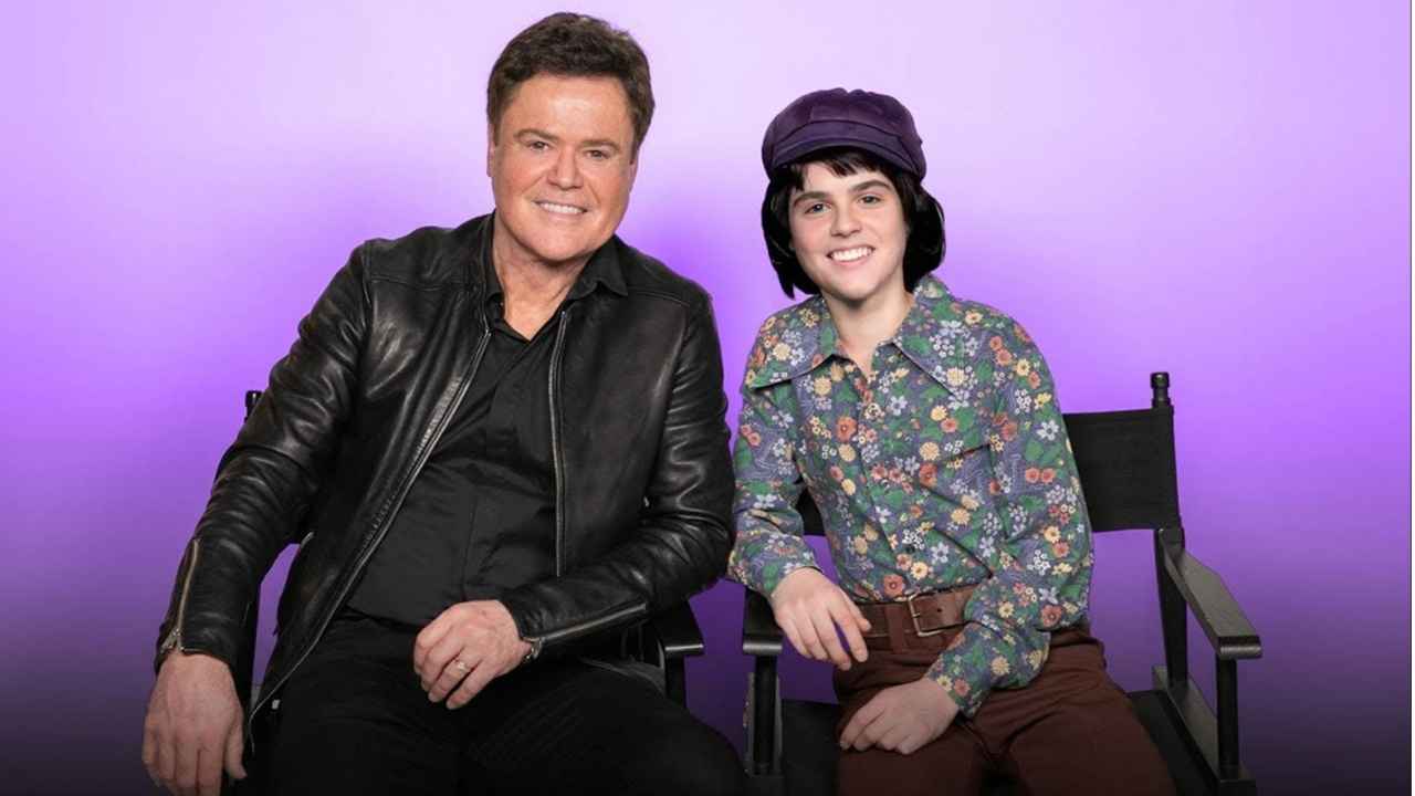 Donny Osmond poses beside the digitally recreated version of his 14-year-old self, built using archived photos, AI modeling and voice samples from his early interviews.